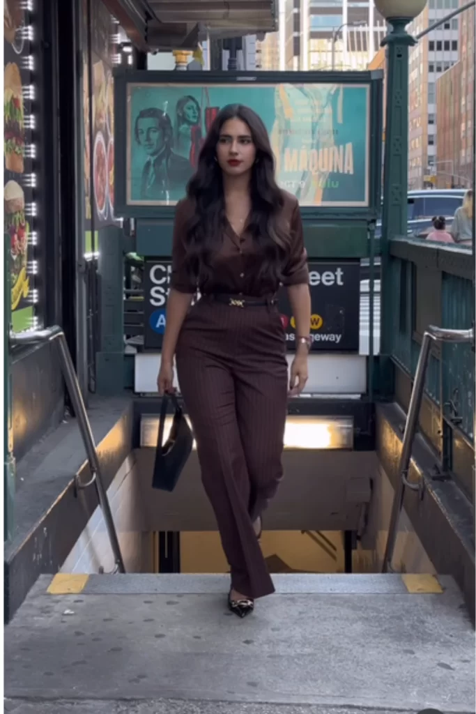 woman walking up from subway wearing chic all brown top with sleeves rolled up and matching pants