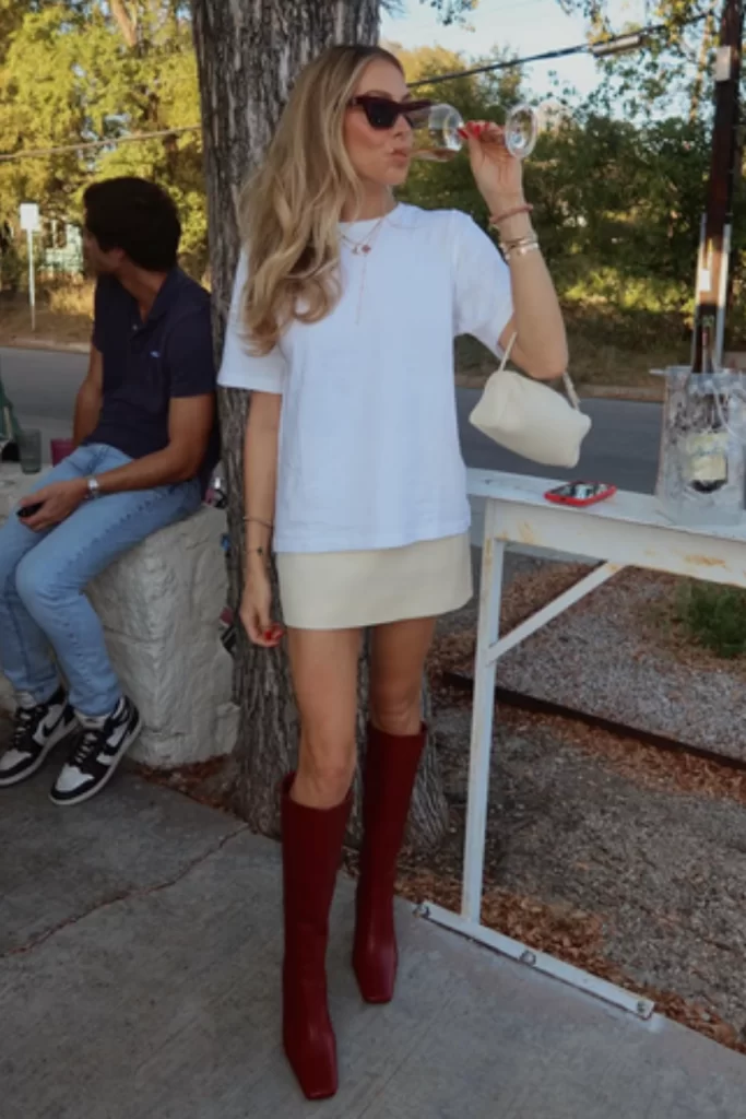 transitional outfit idea for women with woman wearing boxy white tee, cream mini skirt and tall boots