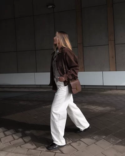 woman walking wearing wide leg white jeans with contrasting black loafers