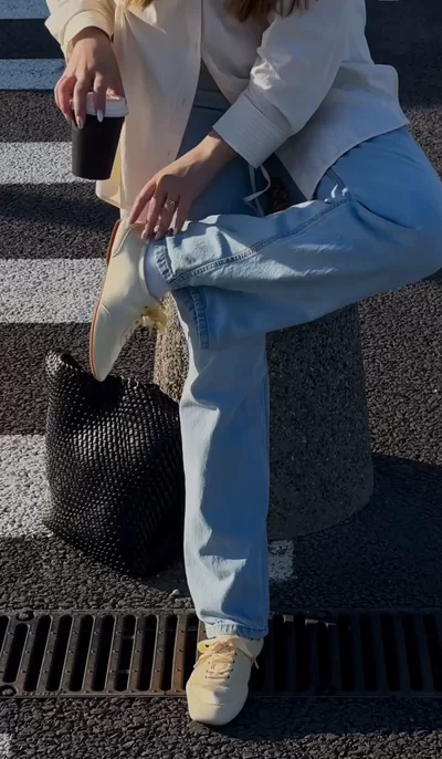 cropped image of woman on street adjusting her ballet flats that are paired with wide leg relaxed jeans