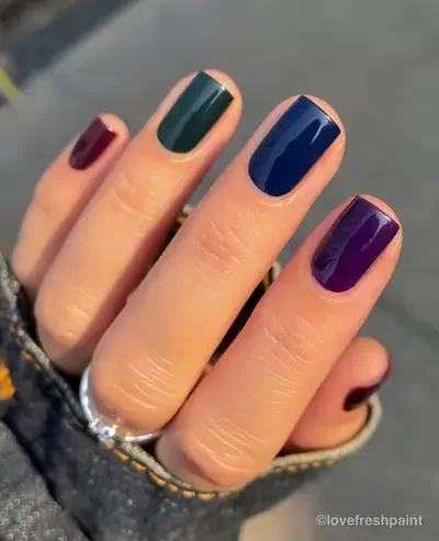 short nail Fall manicure with dark jewel tone colors on each individual finger