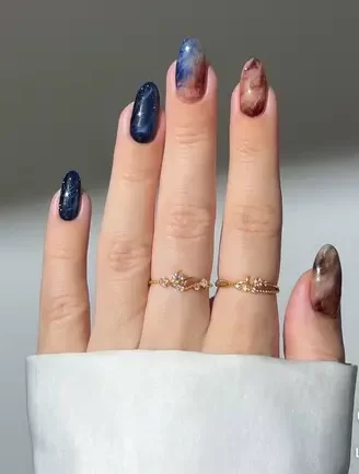 dark galaxy nail art design with blue and brown tones