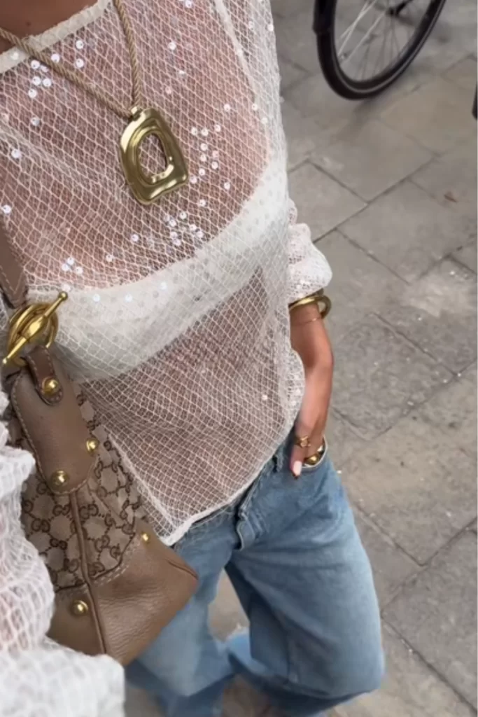 Glam boho outfit with a sheer long sleeve sequin top worn with a bralette paired with blue jeans