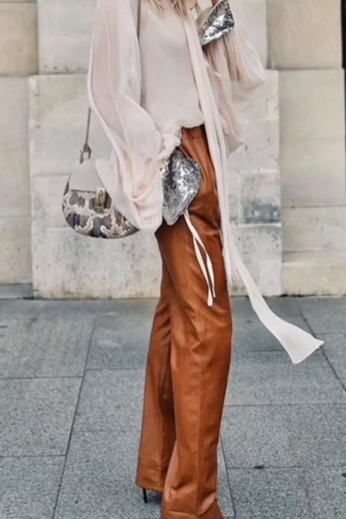 glam fall boho outfit with brown leather trousers and a cream chiffon top with sequin cuffs