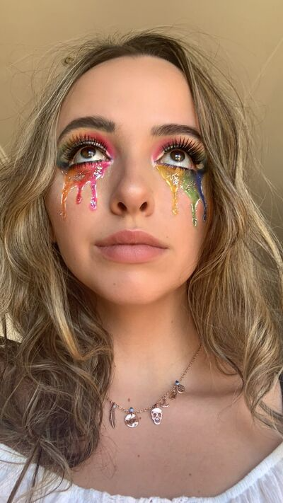 Colorful rainbow glitter tears Halloween makeup idea shown on young blonde woman
