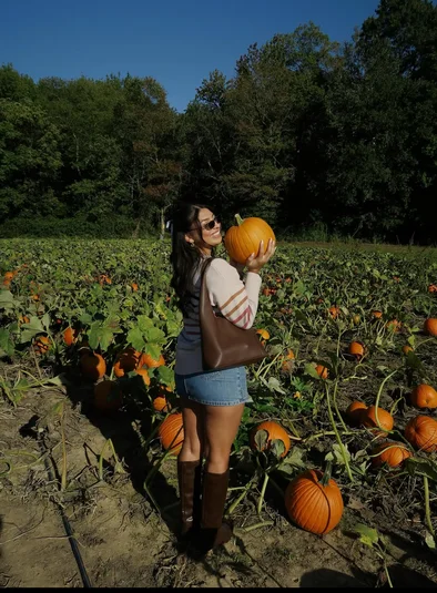 Young woman at pumpkin patch posing with pumpkin