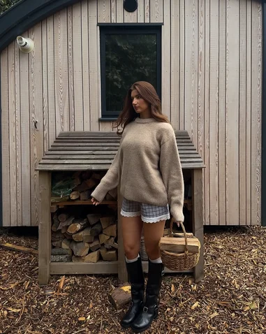 Woman wearing cozy Fall Festival Outfit with ovesized sweater, ruffle shorts and Hunter Boots