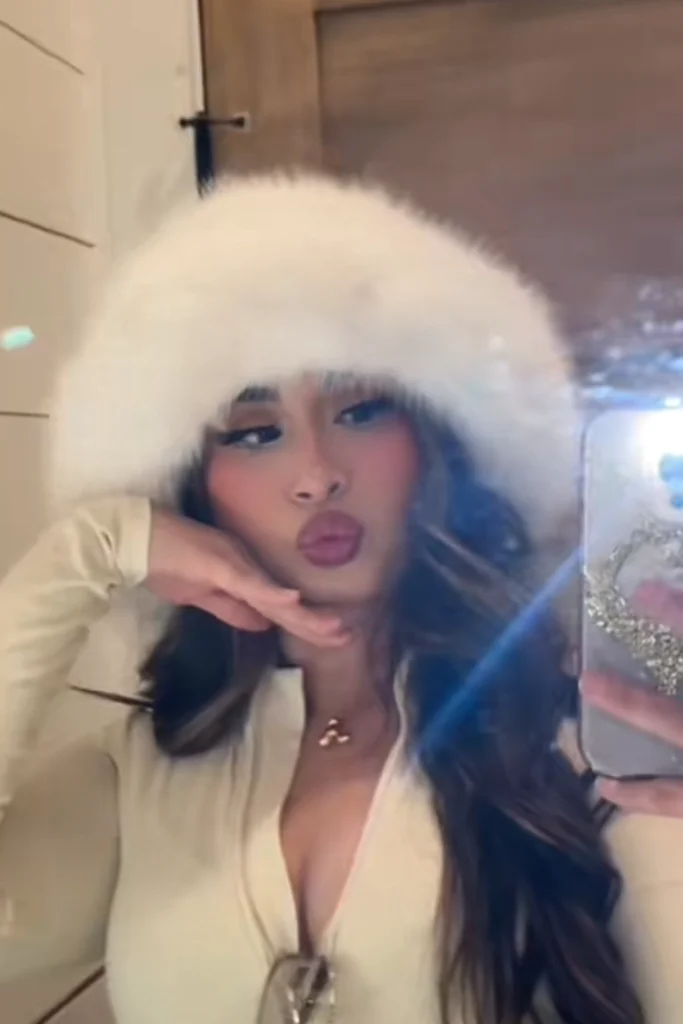 Close up on a woman wearing white long sleeve top and faux fur hat