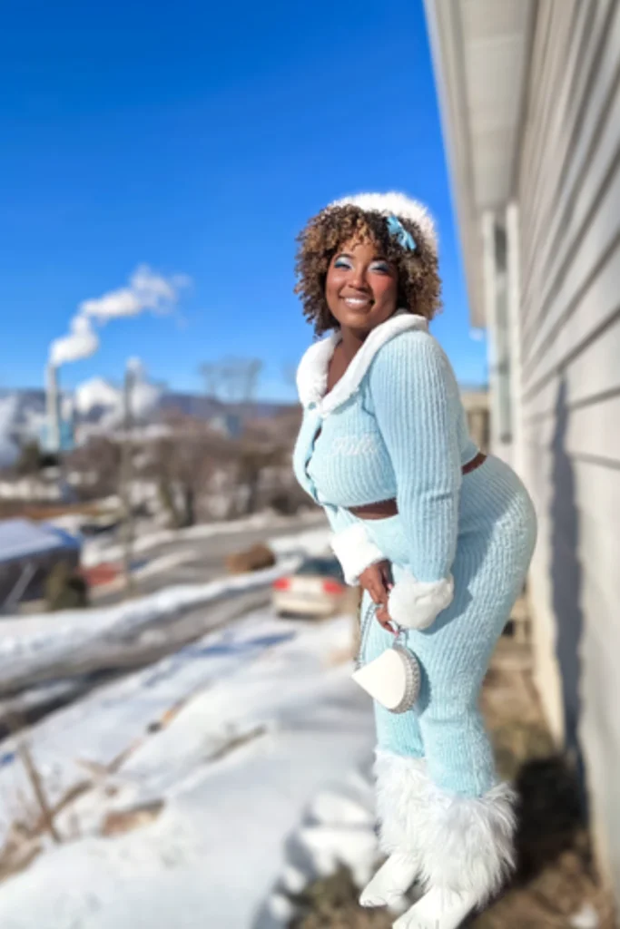 Woman standing outside against snowy background wearing light blue two piece knit set