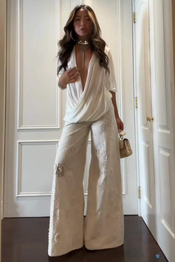 Woman wearing white wide leg embellished pants with drapy white top