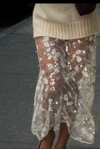Cropped photo of woman wearing cream knit sweater paired with sequin sheer skirt